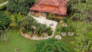 A two-story house with a tiled roof, surrounded by lush greenery and palm trees. - Casa Tropical, Spacious 3 BR Home with Pool (Brasilito)