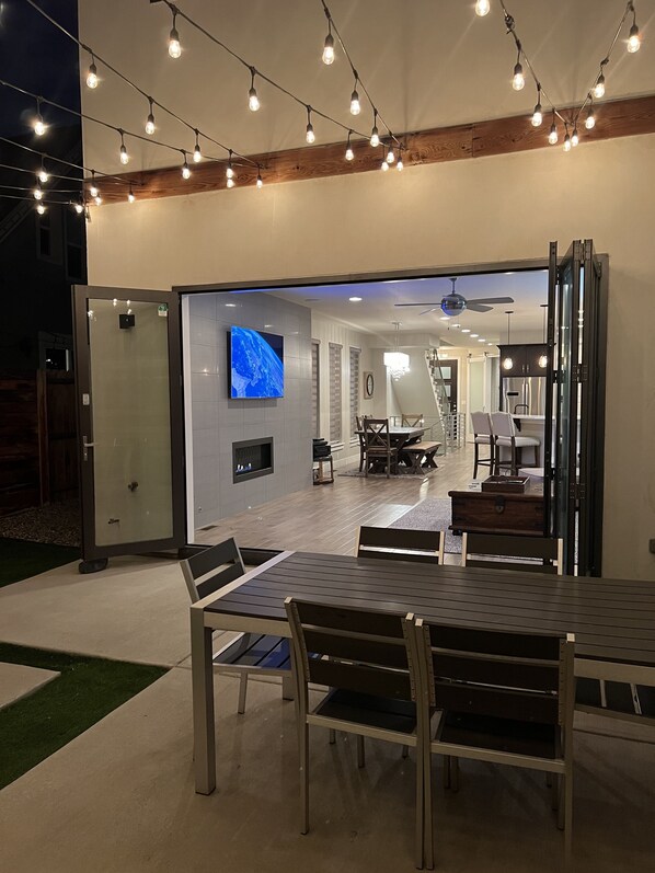 Un comedor interior con diseño moderno, que cuenta con un televisor de pantalla plana grande, mesas y sillas de madera.