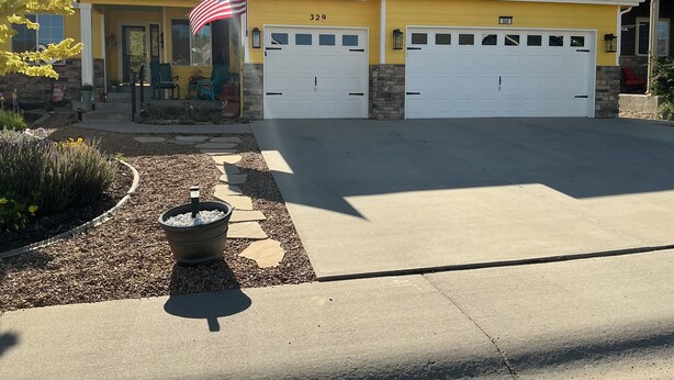 A two-story house with a garage, a driveway, and a flag.