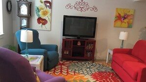 A living room with a television, two sofas, a patterned rug, and wall decorations.