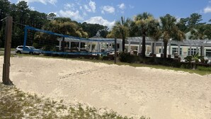 Een hotel aan het strand met een zwembad, overdekte zitplaatsen en palmbomen.