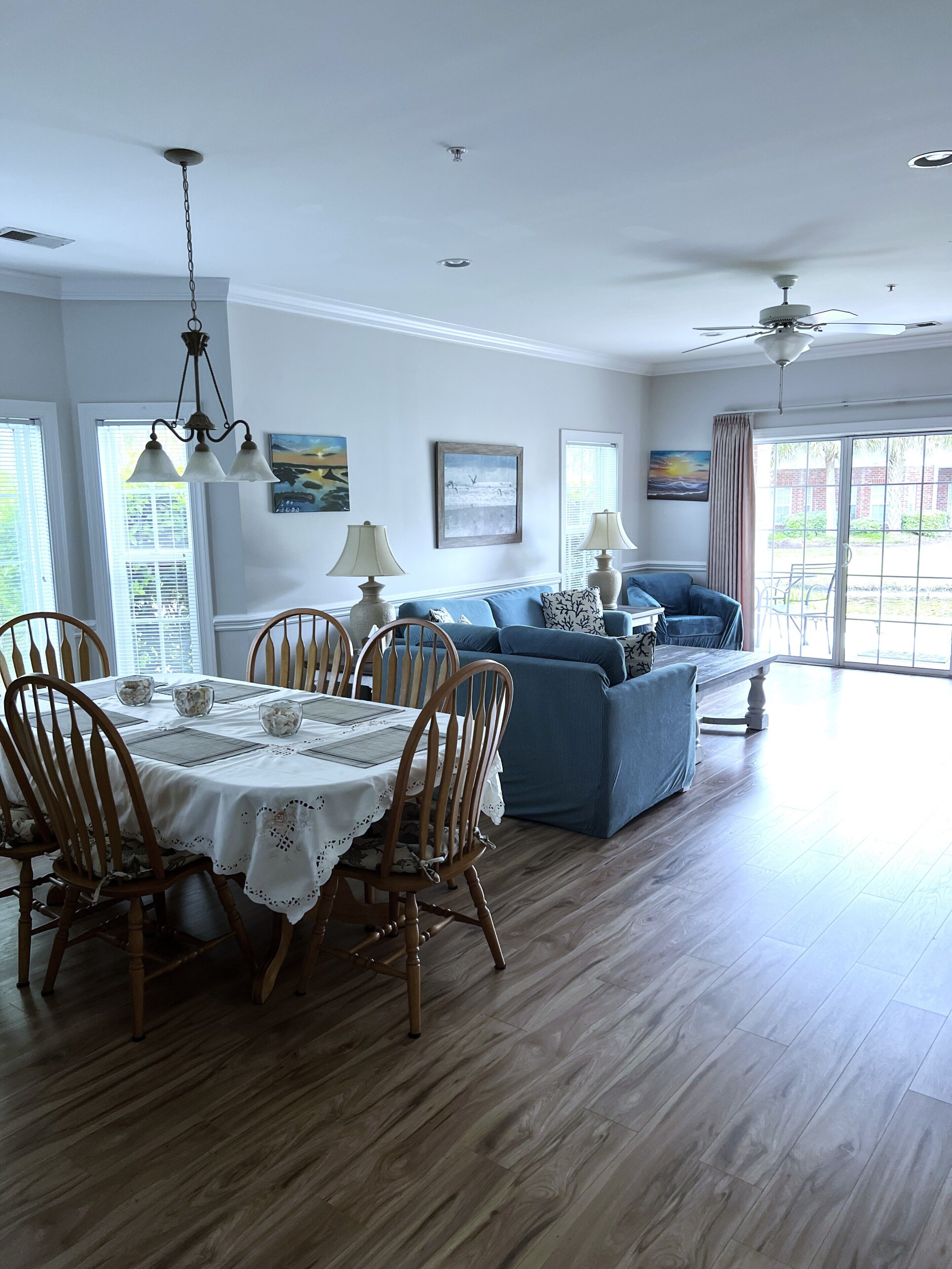A dining area with a table set for four, wooden chairs, and a blue sofa in the background.