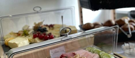 A buffet with various food items including meats, cheeses, and fruits.