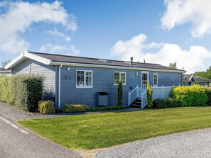 Ett envåningshus med blå fasad, en vit veranda och en liten trädgård framför huset.