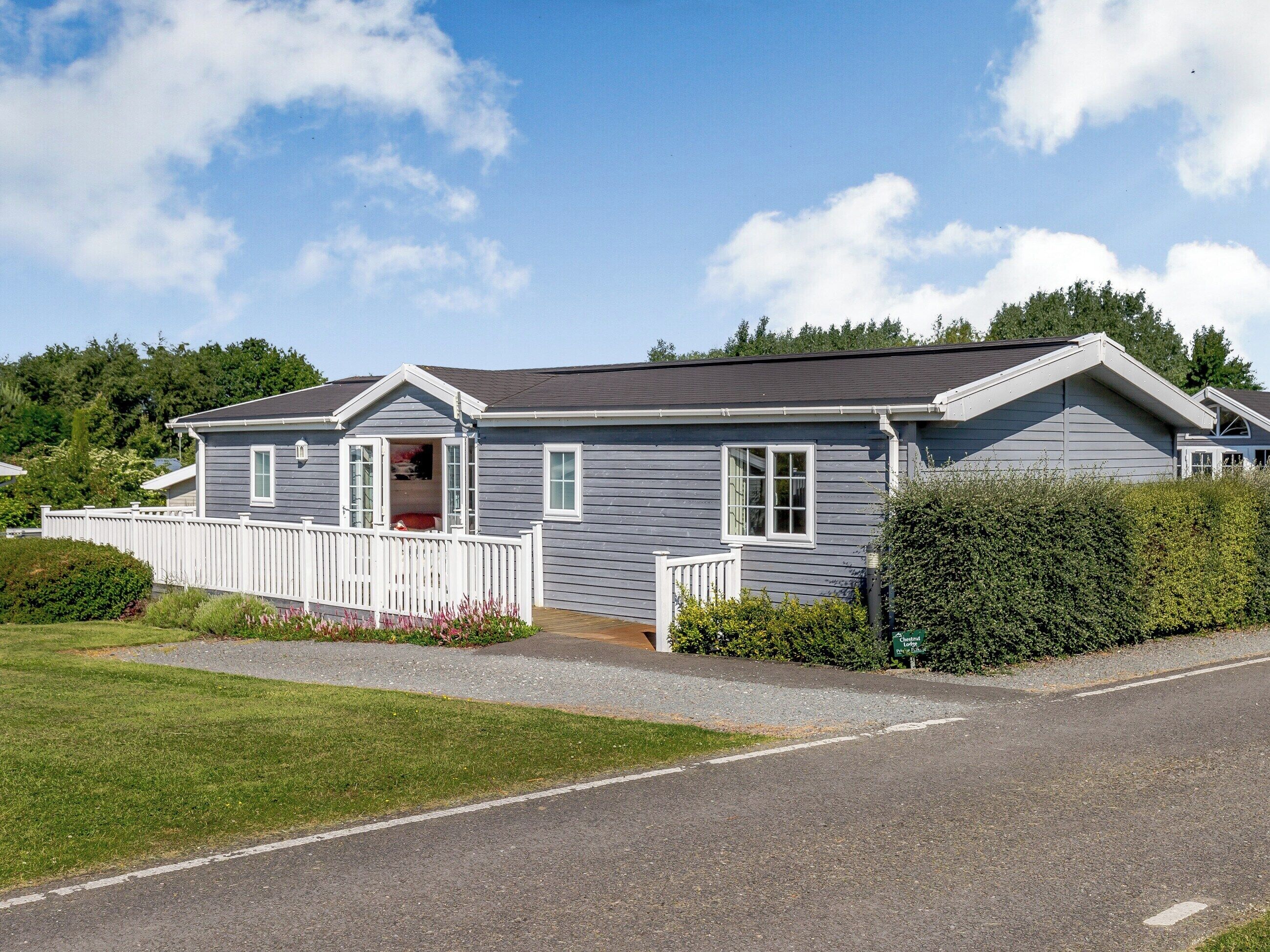 Ein Bungalow mit Veranda, einer kleinen angeschlossenen Garage und einem gepflegten Rasen.