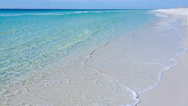 A beach with clear turquoise water and white sand.