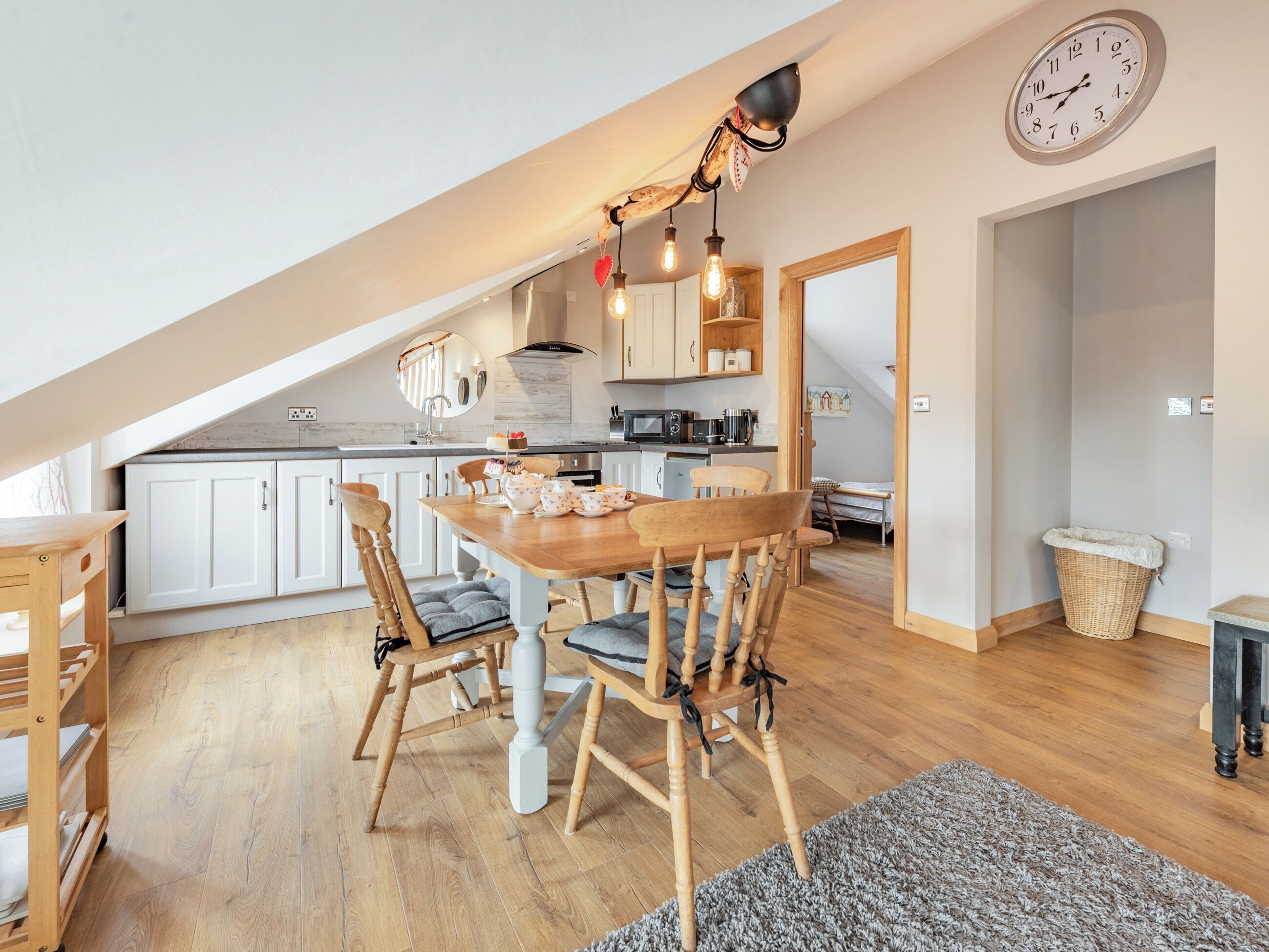 A cozy kitchen with wooden cabinets, a dining table with chairs, and a hanging light fixture.