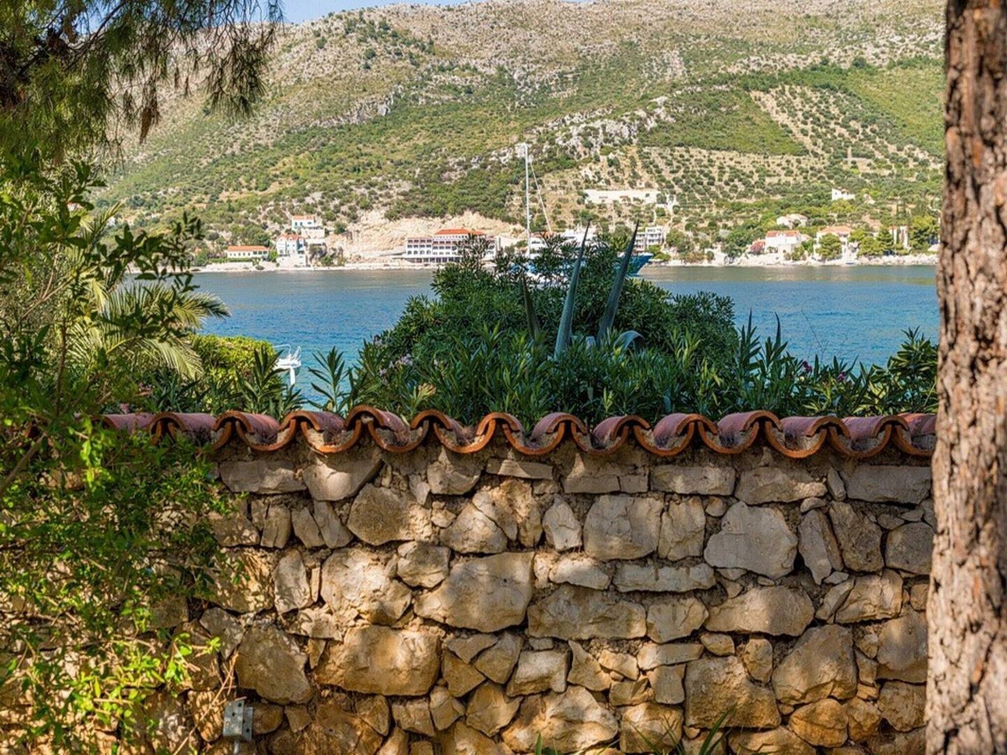 A stone wall with a view of a coastal town and a body of water.