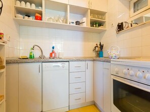 Une cuisine avec des meubles blancs, un lave-vaisselle, un four et un four à micro-ondes.