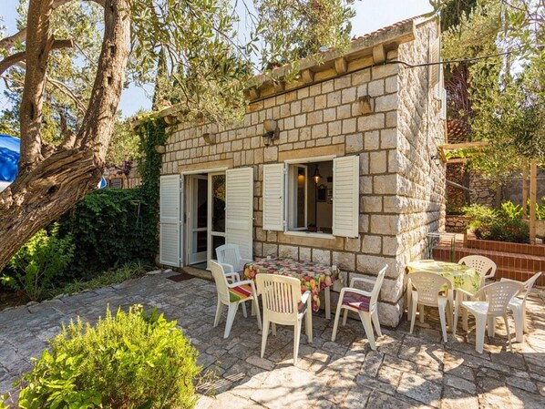 Un bâtiment en pierre doté d’un patio aménagé avec des sièges et une table pour l’extérieur.
