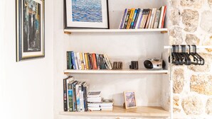 Een boekenplank met boeken en ingelijste foto's tegen een stenen muur.