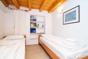 A room with two single beds, a wooden ceiling, white walls, a shelf with pictures and a lamp, and a framed artwork. - Apartments Ribambit- One Bedroom Apartment (First Floor) (Dubrovnik)