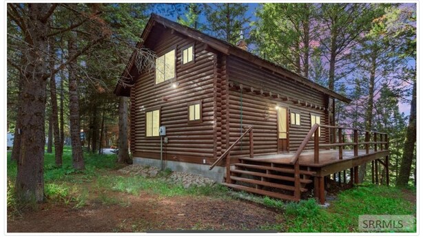 A log cabin with a wooden deck and a staircase leading to the entrance.