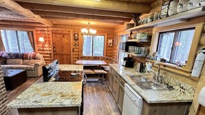 A log cabin with a kitchen featuring granite countertops, wooden cabinets, and a central island.