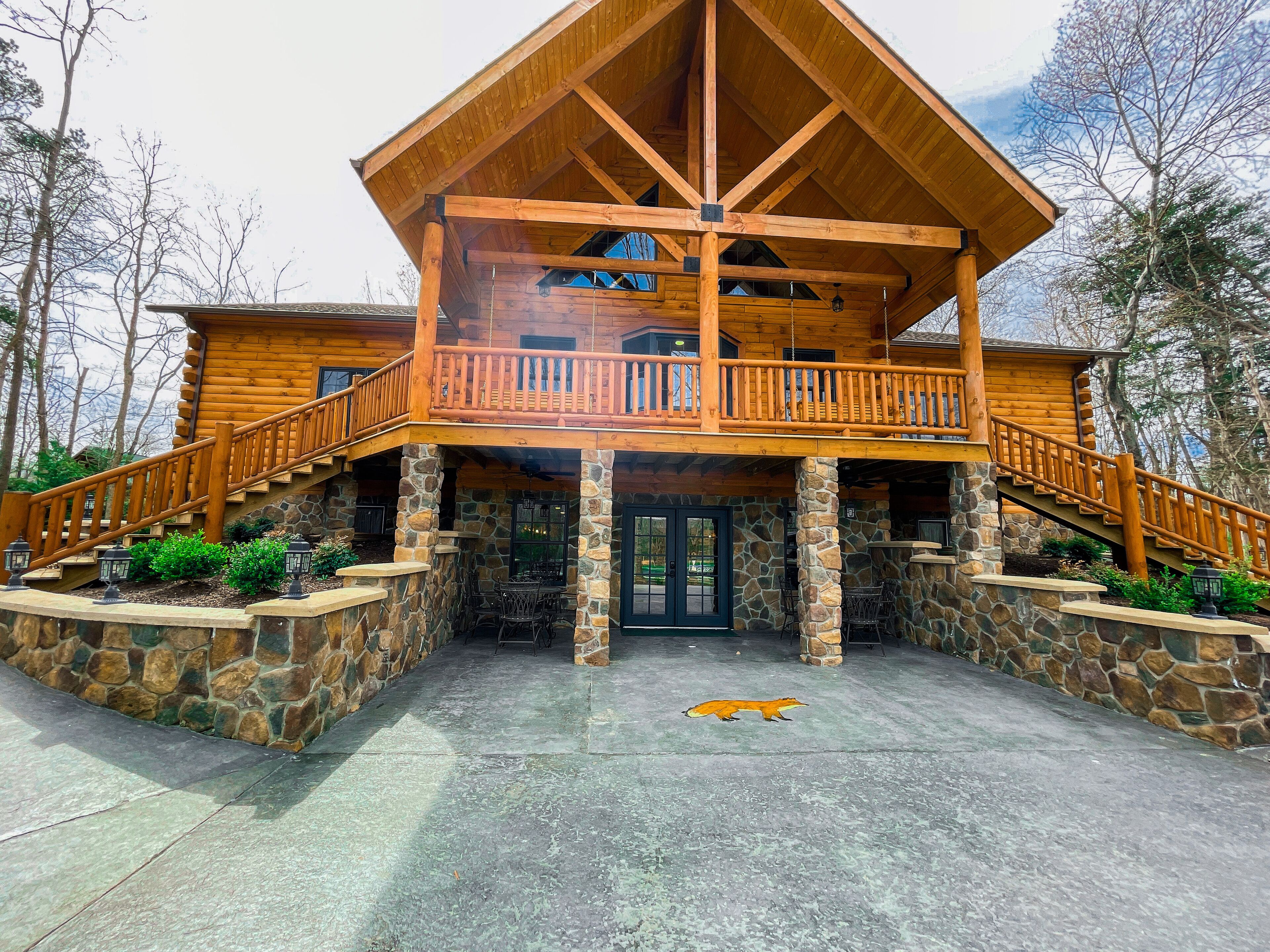 A log cabin with a stone foundation, a wooden balcony, and a stone entrance.