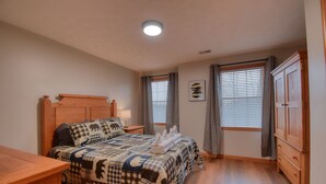 Un dormitorio con cama de madera, una mesita de noche, un armario y una ventana con persianas.