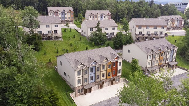 Un barrio residencial con casas de varios pisos, techos a dos aguas y una combinación de colores de revestimiento.