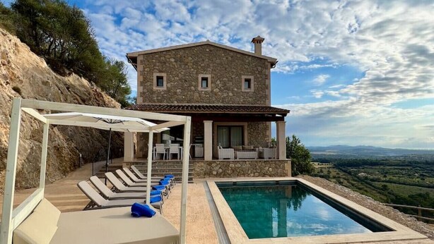 Una casa de piedra con piscina, mobiliario exterior y vistas del paisaje.