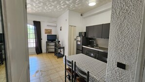 A compact living space with a kitchenette, a dining area with a patterned table, and a television in the background.