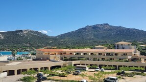 A building with multiple floors, a parking area, and a mountainous backdrop.