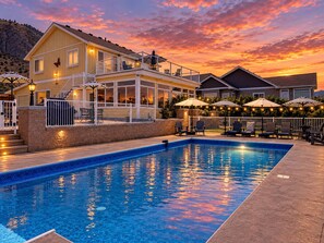 Ein Schwimmbad mit Blick auf ein Haus und einen Sonnenuntergang.