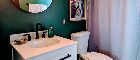 A bathroom with a white sink, a toilet, a mirror, and a shower curtain.