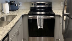 Una cucina moderna con elettrodomestici in acciaio inox, un forno a microonde, un forno e un frigorifero.