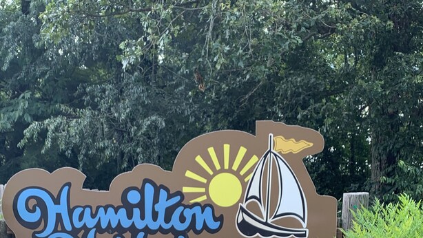 Segnale pubblicitario per i Condomini Hamilton Harbor, con un'immagine di una barca a vela e del sole.