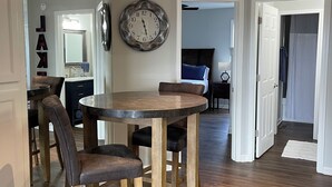 Zona pranzo con tavolo e sedie in legno, orologio a parete e lampadario.