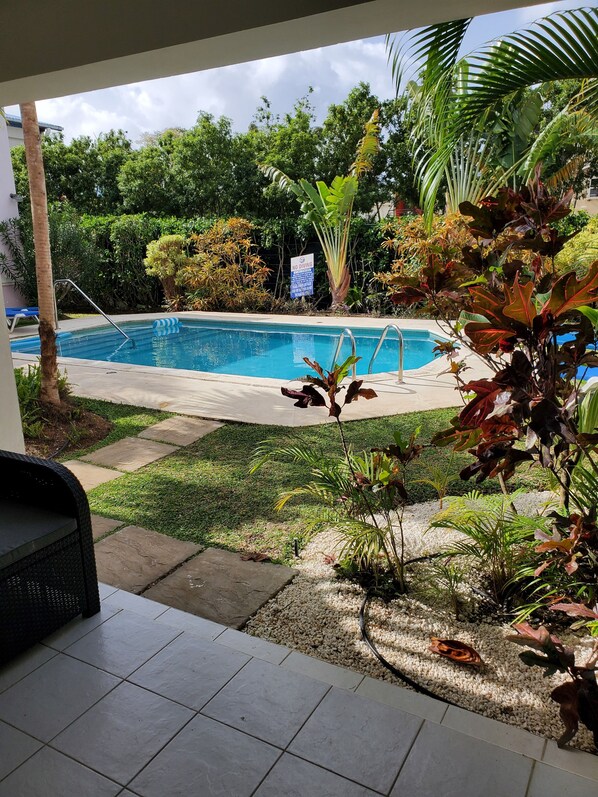 A swimming pool with a 'No Diving' sign, surrounded by lush greenery and a tiled patio area.