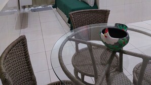 Ein Hotelzimmer mit einem Bett, einer grünen Bettdecke, einer weißen Wand mit einer rot-orangenen Flagge, einem weißen Nachttisch, einem weißen Stuhl und einem Glastisch mit einem dekorativen Gegenstand.