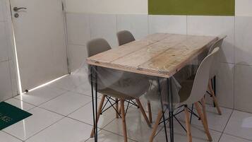 A dining area with a rectangular table, six chairs, and a white tiled floor.