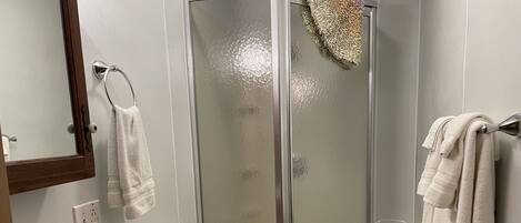 Ein Badezimmer mit einer Duschkabine, Toilette, Waschbecken und Spiegel.