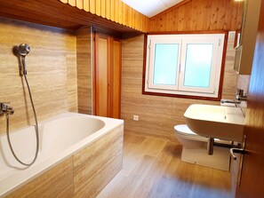 Een bad/douchecombinatie, een haardroger, handdoeken, zeep