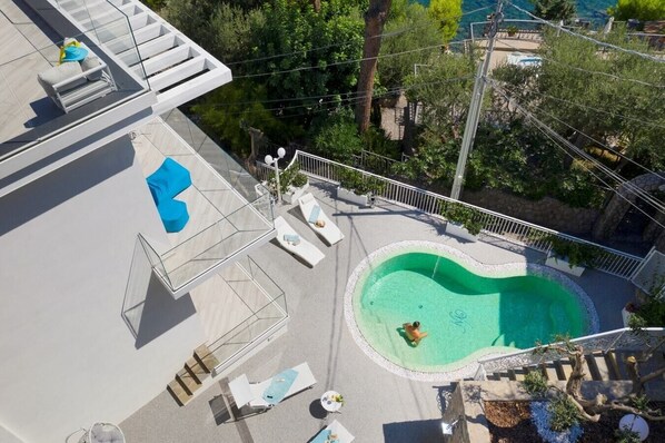 Un área de piscina en la azotea con sillones de descanso y una piscina.