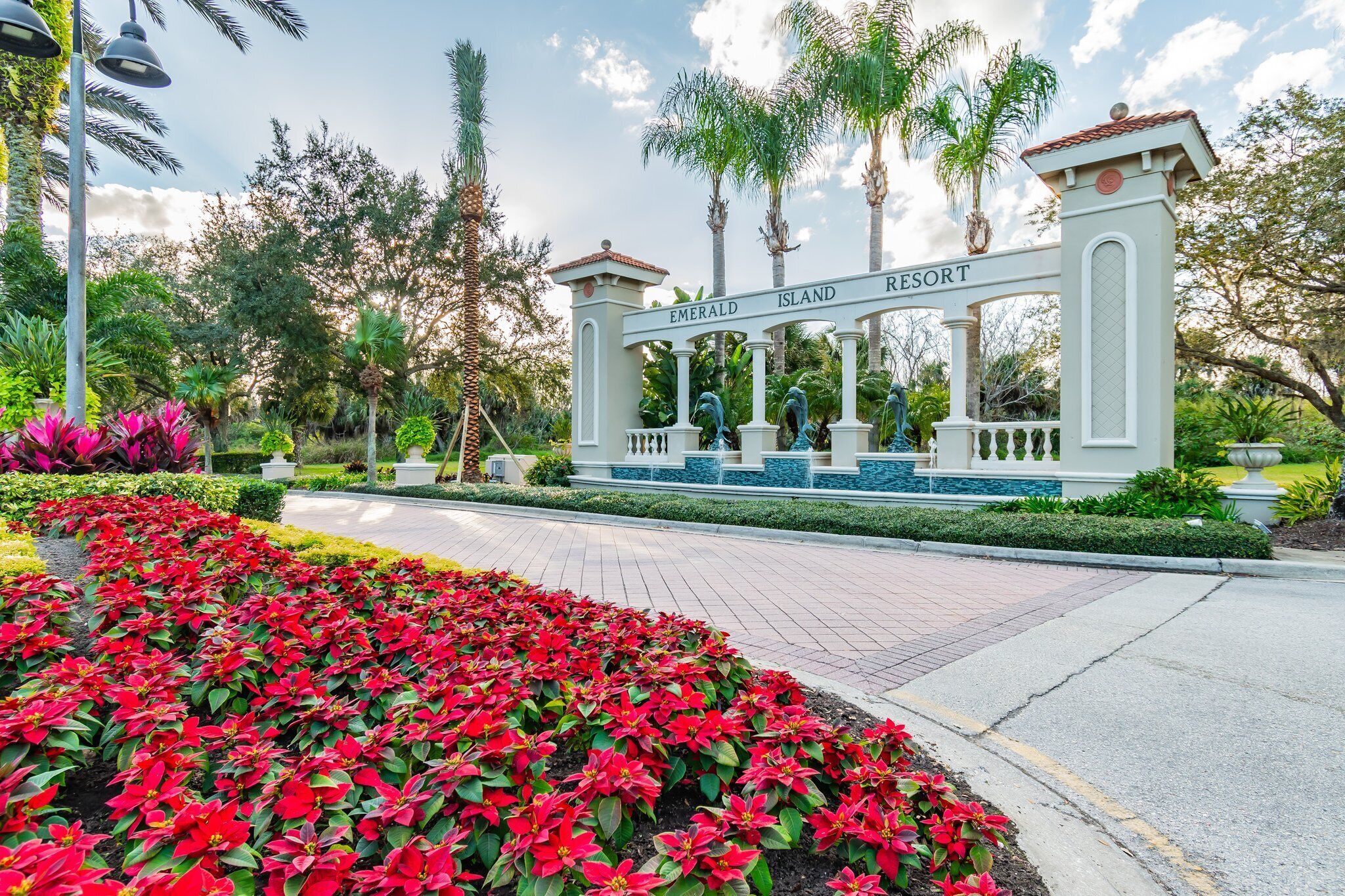 A sign for Emerald Island Resort with a well-maintained garden and palm trees.