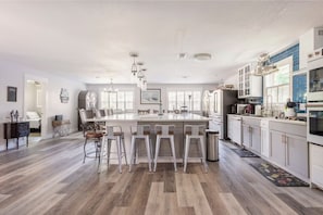 Uma cozinha espaçosa com uma ilha grande, banquetas e eletrodomésticos modernos.