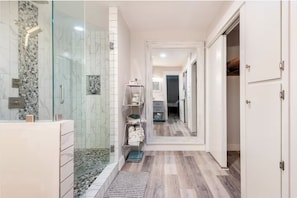 Um banheiro moderno com chuveiro de vidro, toucador e closet espaçoso.