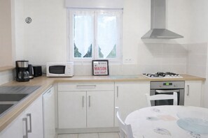 A kitchen with a microwave, coffee maker, gas stove, and a sign on the window.