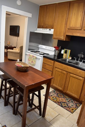 Compact kitchen area with a dining table and chairs, wooden cabinetry, and a stove.