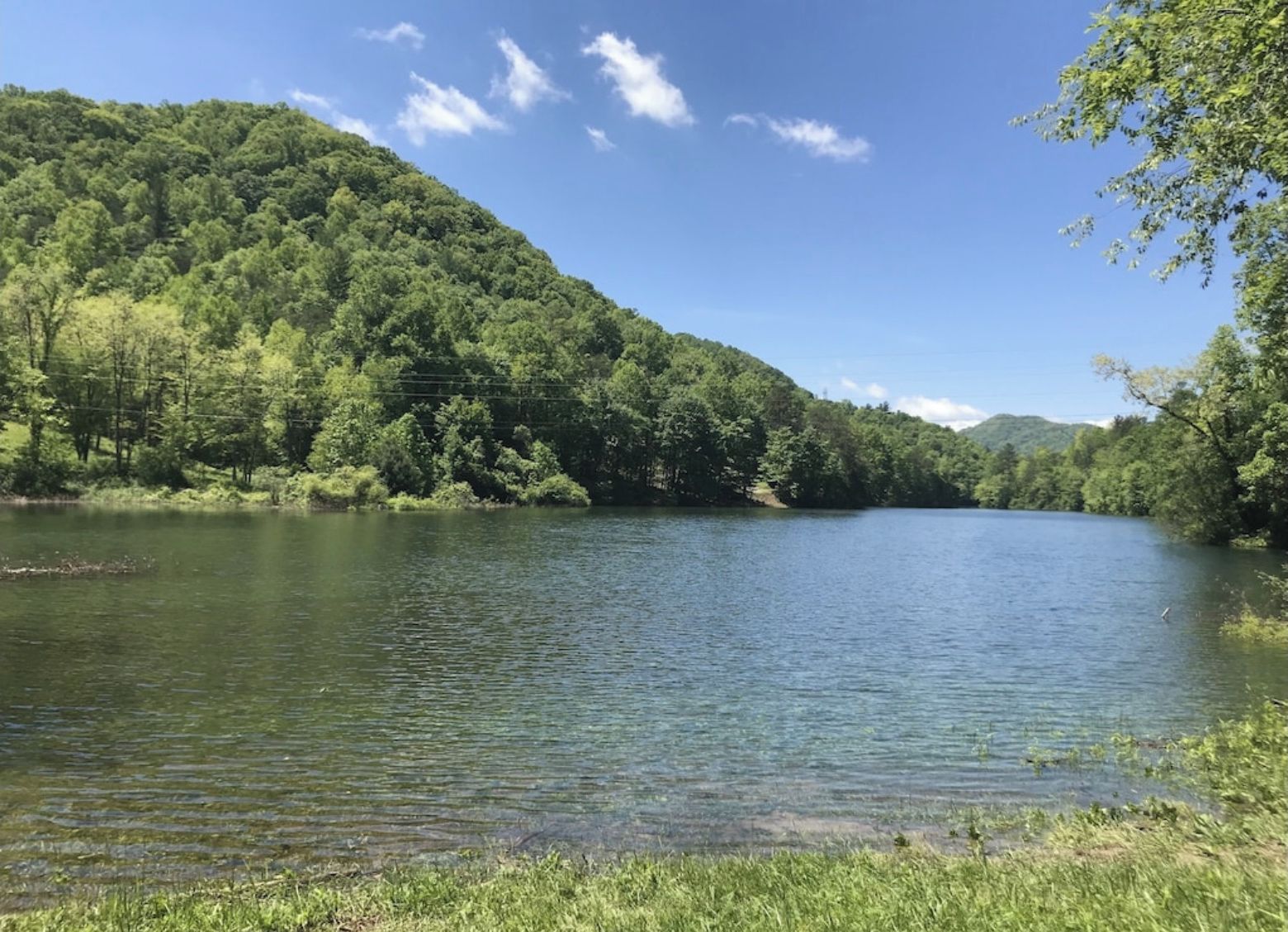A serene lake surrounded by lush green hills and trees.