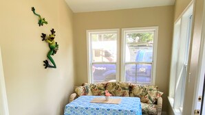 Una habitación con piso estampado, una mesa con mantel azul, un sofá con cojines florales y un adorno de pared verde.