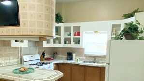 Una cocina con una isla central, armarios blancos, un refrigerador blanco y un cesto de basura.