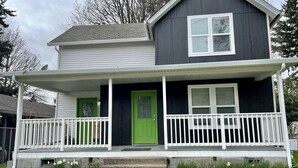 A two-story house with a front porch, a green door, and a white railing. - Spacious 1bd/1bt downtown apartment next to the park (Vancouver)