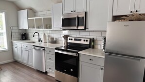A modern kitchen with white cabinetry, a stainless steel refrigerator, a microwave, an oven, and a dishwasher. - Spacious 1bd/1bt downtown apartment next to the park (Vancouver)