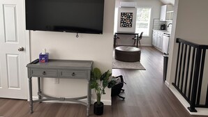 A modern living room with a flat-screen TV, a grey console table, a round ottoman, and a potted plant. - Spacious 1bd/1bt downtown apartment next to the park (Vancouver)