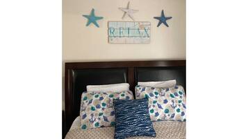 Une chambre à coucher avec un lit agrémenté d’oreillers à motifs et une décoration murale représentant des étoiles et le mot « RELAX ».