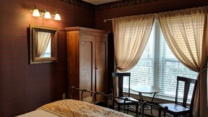 Ein Hotelzimmer mit einem Bett, einem Holzschrank, einem Schreibtisch mit Stühlen und einem Fenster mit Vorhängen.