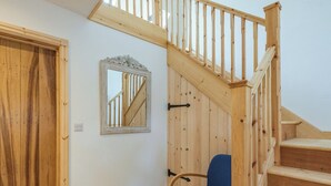 A wooden staircase with a handrail and a chair in a room with wooden walls and a door.