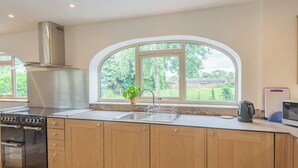 A modern kitchen with a large window, stainless steel appliances, and wooden cabinets.